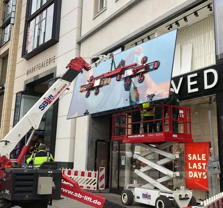 Kran mit Saugheber setzt eine große Schaufensterscheibe in eine Ladenfassade ein